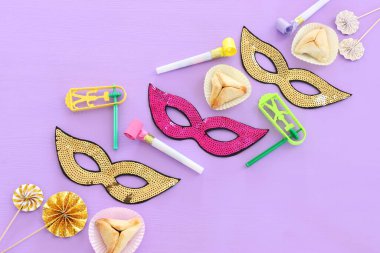 Purim kutlaması konsepti (Yahudi karnavalı tatili) ahşap mor arka planda. Üst manzara, düz uzanma