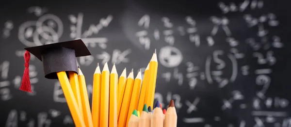 Bleistifte Und Graduiertenmütze Vor Der Tafel Mit Formeln Bildungskonzept — Stockfoto