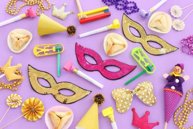 Purim kutlaması konsepti (Yahudi karnavalı tatili) ahşap mor arka planda. Üst manzara, düz uzanma