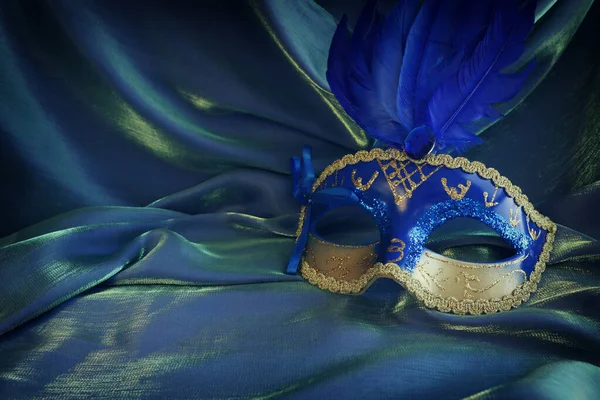 青の絹の背景の上にエレガントで繊細なヴェネツィアのマスクの写真 — ストック写真