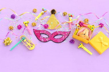 Purim kutlaması konsepti (Musevi karnaval bayramı) mor ahşap arka plan üzerine