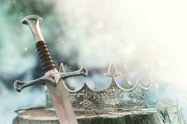 İngiltere ormanlarındaki altın kral tacının ve kılıcın gizemli ve sihirli fotoğrafı. Ortaçağ konsepti.