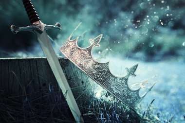 İngiltere ormanlarındaki altın kral tacının ve kılıcın gizemli ve sihirli fotoğrafı. Ortaçağ konsepti.