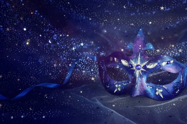 Mavi siyah yıldızların arka planında zarif ve narin Venedik maskesinin fotoğrafı