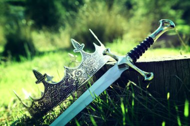 İngiltere ormanlarındaki altın kral tacının ve kılıcın gizemli ve sihirli fotoğrafı. Ortaçağ konsepti