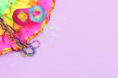 Mor arka planda Mardi Gras maskesi tatili görüntüsü. Yukarıdan görünüm