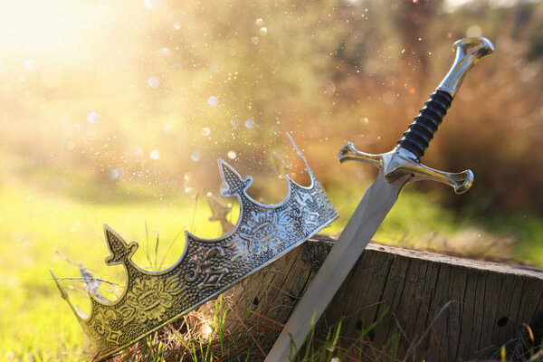 Mysterious and magical photo of gold king crown and sword in the England woods. Medieval period concept.