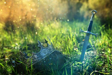 İngiltere ormanlarındaki altın kral tacının ve kılıcın gizemli ve sihirli fotoğrafı. Ortaçağ konsepti.