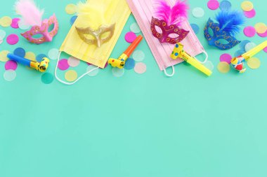 Maskeli balo maskesi arkaplanının en üst görünümü. Düz yatıyordu. Purim kutlaması (Yahudi karnavalı bayramı). Coronavirus önleme konsepti, tıbbi maske