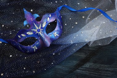 Mavi siyah yıldızların arka planında zarif ve narin Venedik maskesinin fotoğrafı