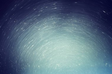 Karanlık gökyüzünde soyut parıltılı yıldızlar parlıyor