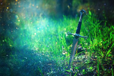 İngiltere ormanlarında gümüş kılıcın gizemli ve sihirli fotoğrafı ve ışık fişeği. Ortaçağ konsepti