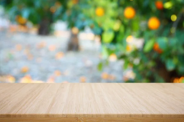 Empty wooden table in front of orange field