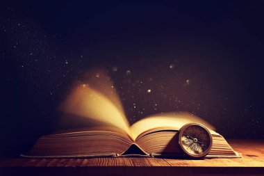 Tahta masanın üzerinde parıltılı kaplamalı açık antik kitap görüntüsü