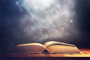 Tahta masanın üzerinde parıltılı kaplamalı açık antik kitap görüntüsü