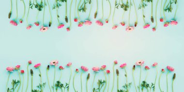 Mavi pastel arkaplan üzerindeki pembe çiçeklerin üst görünümü