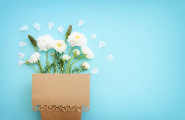 Beyaz çiçeklerin üst görünümü bileşimi ve mavi pastel arkaplan üzerine boş nota