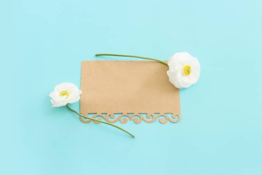 Beyaz çiçeklerin üst görünümü bileşimi ve mavi pastel arkaplan üzerine boş nota