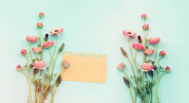 Pembe çiçeklerin üst görünümü kompozisyonu ve mavi pastel arkaplan üzerine boş nota