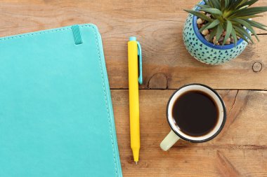 Ahşap masanın üstünde defter ve kahve resmi var. Metin ya da model eklemeye hazır.