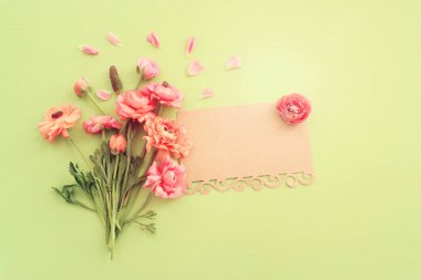 Pembe çiçeklerin üst görünümü kompozisyonu ve yeşil ahşap arkaplan üzerine boş nota