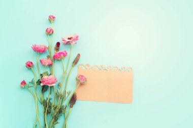 Pembe çiçeklerin üst görünümü kompozisyonu ve mavi pastel arkaplan üzerine boş nota