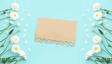 Beyaz çiçeklerin üst görünümü bileşimi ve mavi pastel arkaplan üzerine boş nota
