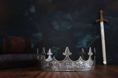 Güzel kraliçe ya da kral tacının gösterişsiz görüntüsü, kılıcın yanında antika bir kitap. fantezi ortaçağ dönemi. Seçici odak