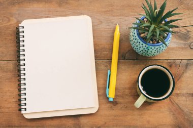 top view image of open notebook with blank pages and cup of coffee over wooden desk. ready for adding text or mockup.