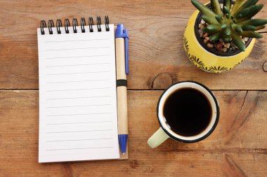 top view image of open notebook with blank pages and cup of coffee over wooden desk. ready for adding text or mockup.