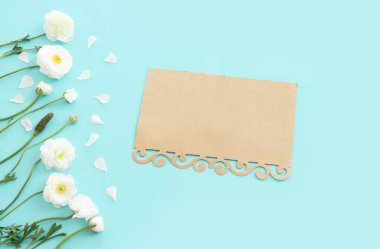 Beyaz çiçeklerin üst görünümü bileşimi ve mavi pastel arkaplan üzerine boş nota