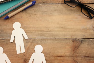 Bir grup insan, toplumun sembolü, takım çalışması ve ahşap masa üzerinde işbirliği.