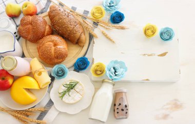 Süt ürünlerinin beyaz ahşap zemin üzerindeki en iyi görüntüsü. Yahudi bayramının sembolleri - Shavuot