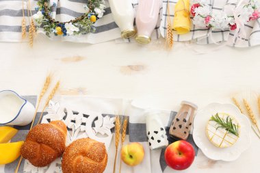 Süt ürünlerinin beyaz ahşap zemin üzerindeki en iyi görüntüsü. Yahudi bayramının sembolleri - Shavuot