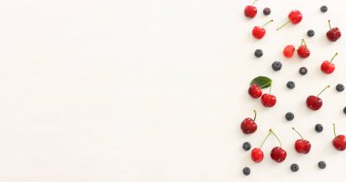 Böğürtlen, böğürtlen ve kiraz karışımının ahşap beyaz arka planda renkli görüntüsü.