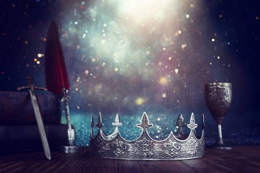 low key image of beautiful queen or king crown next to sword. fantasy medieval period. Selective focus