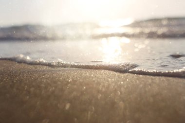 Deniz dalgaları ve ılık gün batımı ışığı, sakin ve rahatlatıcı kumsal