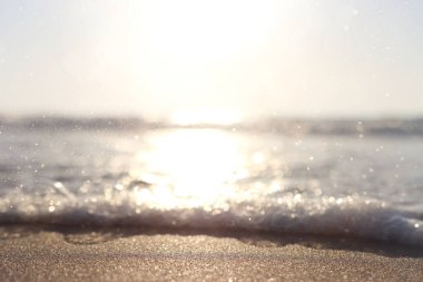 Deniz dalgaları ve ılık gün batımı ışığı, sakin ve rahatlatıcı kumsal