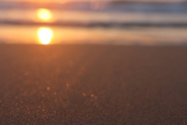 Deniz dalgaları ve ılık gün batımı ışığı, sakin ve rahatlatıcı kumsal