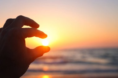 Akşamları güneşi tutan eller. Deniz arka planı. Yaz ve tatil konsepti