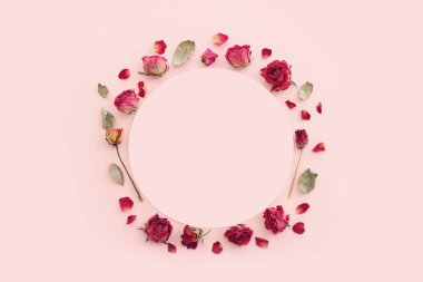 Üzerinde pembe pastel arkaplan olan kuru gül çiçeklerinin üst görünümü