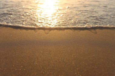 Deniz dalgaları ve ılık gün batımı ışığı, sakin ve rahatlatıcı kumsal