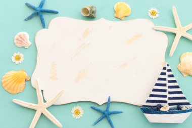 Yelkenli tekne, deniz kabukları, yıldız balığı ve nane mavisi ahşap arka planda fotokopi alanı için boş tahta.