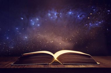 Tahta masanın üzerinde parıltılı kaplamalı açık antik kitap görüntüsü