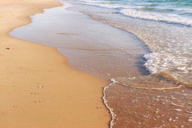 Deniz dalgaları ve ılık gün batımı ışığı, sakin ve rahatlatıcı kumsal