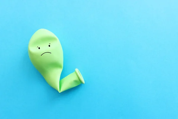 青い背景に悲しい顔をした気球のトップビュー画像 感情や悲しみやストレスの概念 — ストック写真