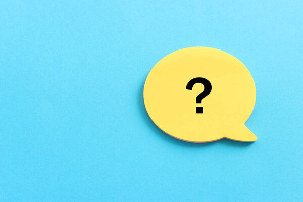 Top view image of sticky note and question mark over textured paper