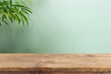 wooden table in front of interior wall and tropical green plant background. for product display and presentation.