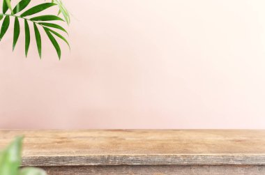 wooden table in front of interior wall and tropical green plant background. for product display and presentation.