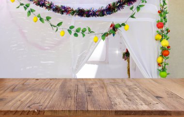 Jewish festival of Sukkot. Traditional succah (hut) with decorations. Empty wooden old table for product display and presentation. clipart